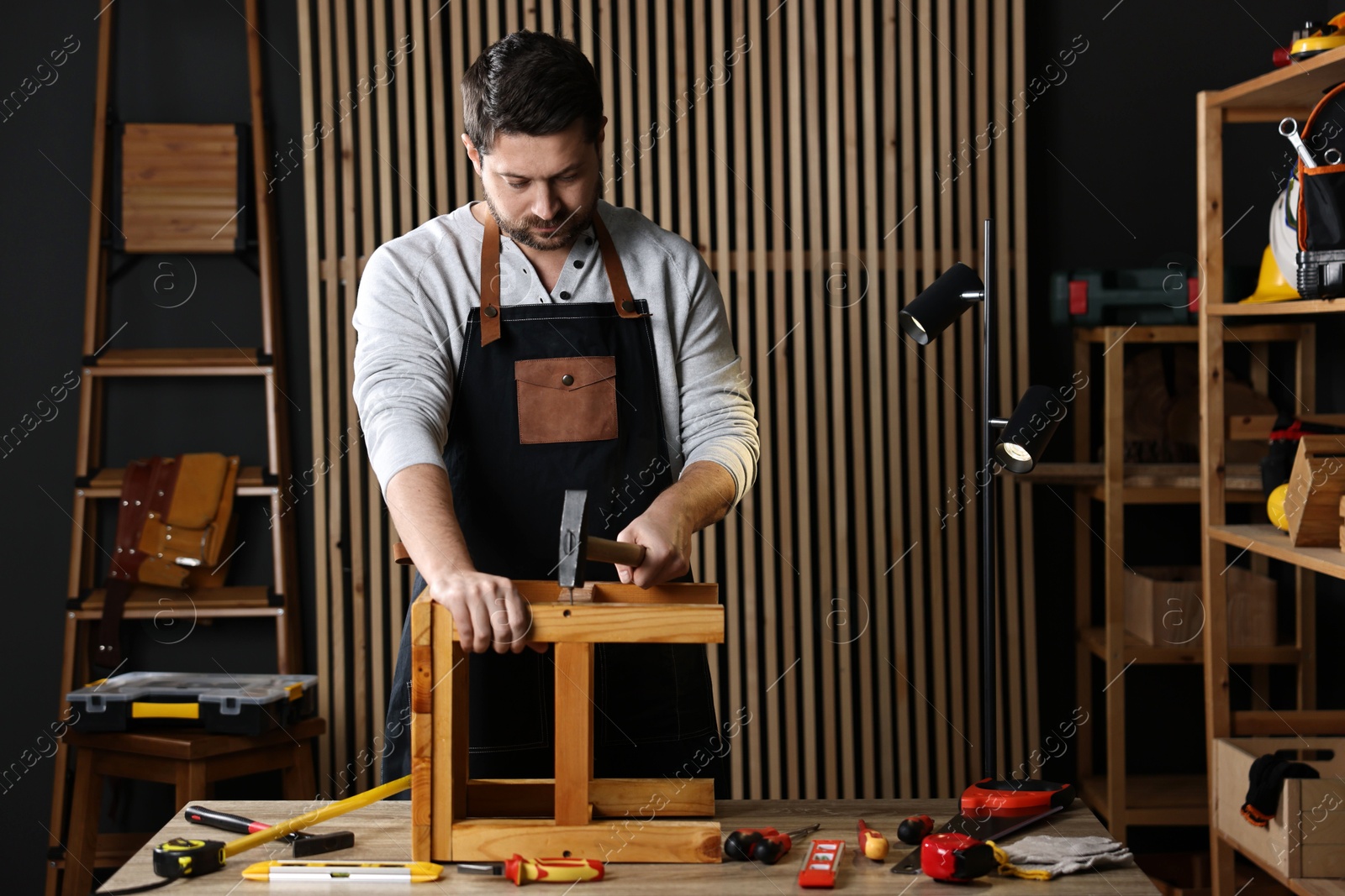 Photo of Carpenter repairing stool at table in workshop