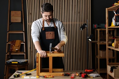 Photo of Carpenter repairing stool at table in workshop