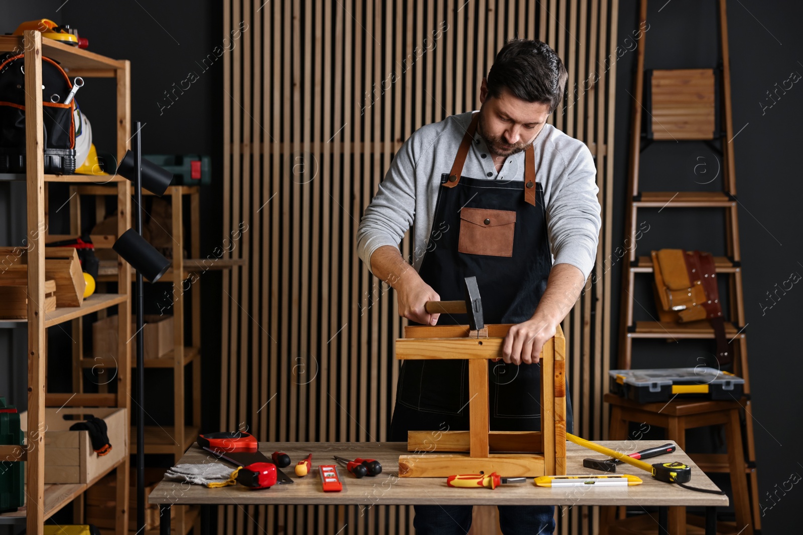 Photo of Carpenter repairing stool at table in workshop