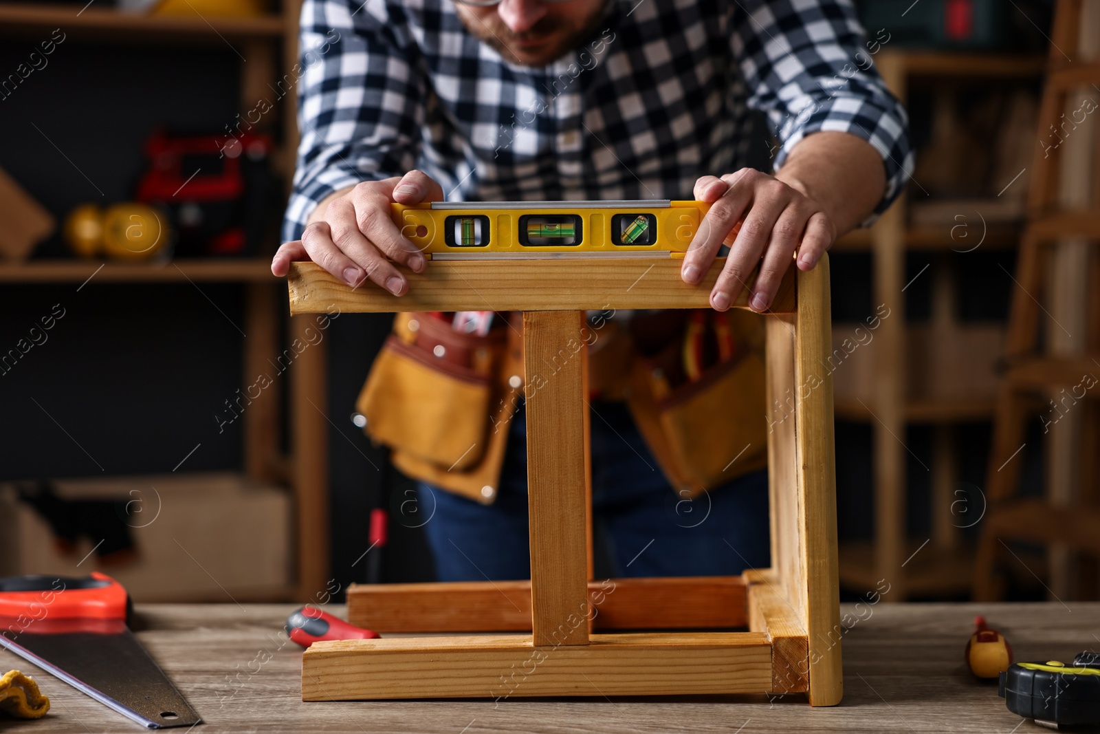 Photo of Repairman checking stool level at table in workshop, closeup