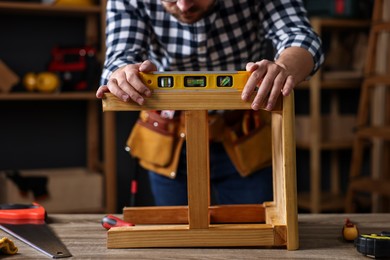 Photo of Repairman checking stool level at table in workshop, closeup