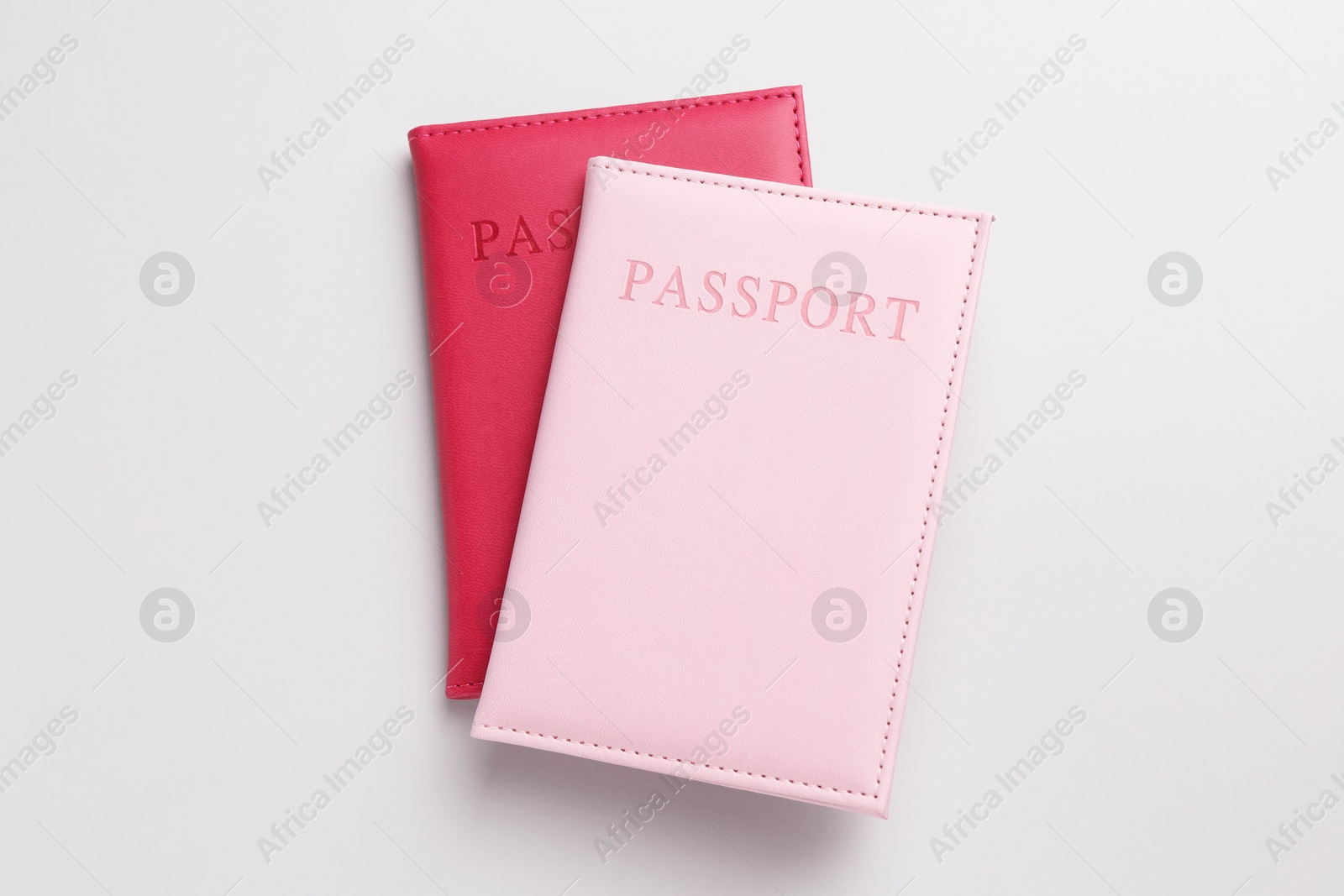 Photo of Passports in color covers on light background, top view