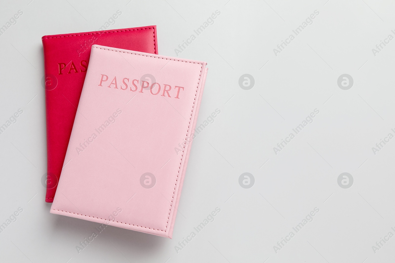 Photo of Passports in color covers on light background, top view. Space for text