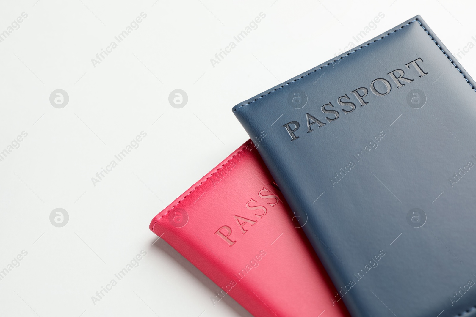 Photo of Passports in color covers on light background, closeup. Space for text