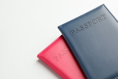 Photo of Passports in color covers on light background, closeup. Space for text