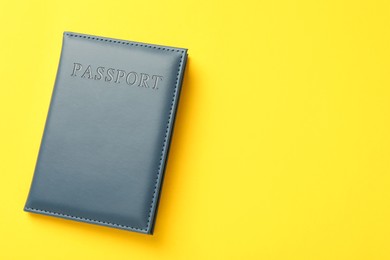 Photo of Passport in dark blue cover on yellow background, top view. Space for text