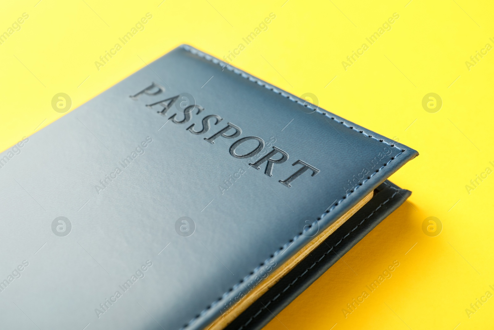 Photo of Passport in dark blue cover on yellow background, closeup