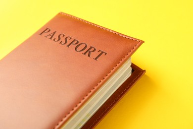 Photo of Passport in brown cover on yellow background, closeup