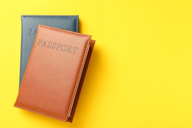 Photo of Passports in color covers on yellow background, top view. Space for text