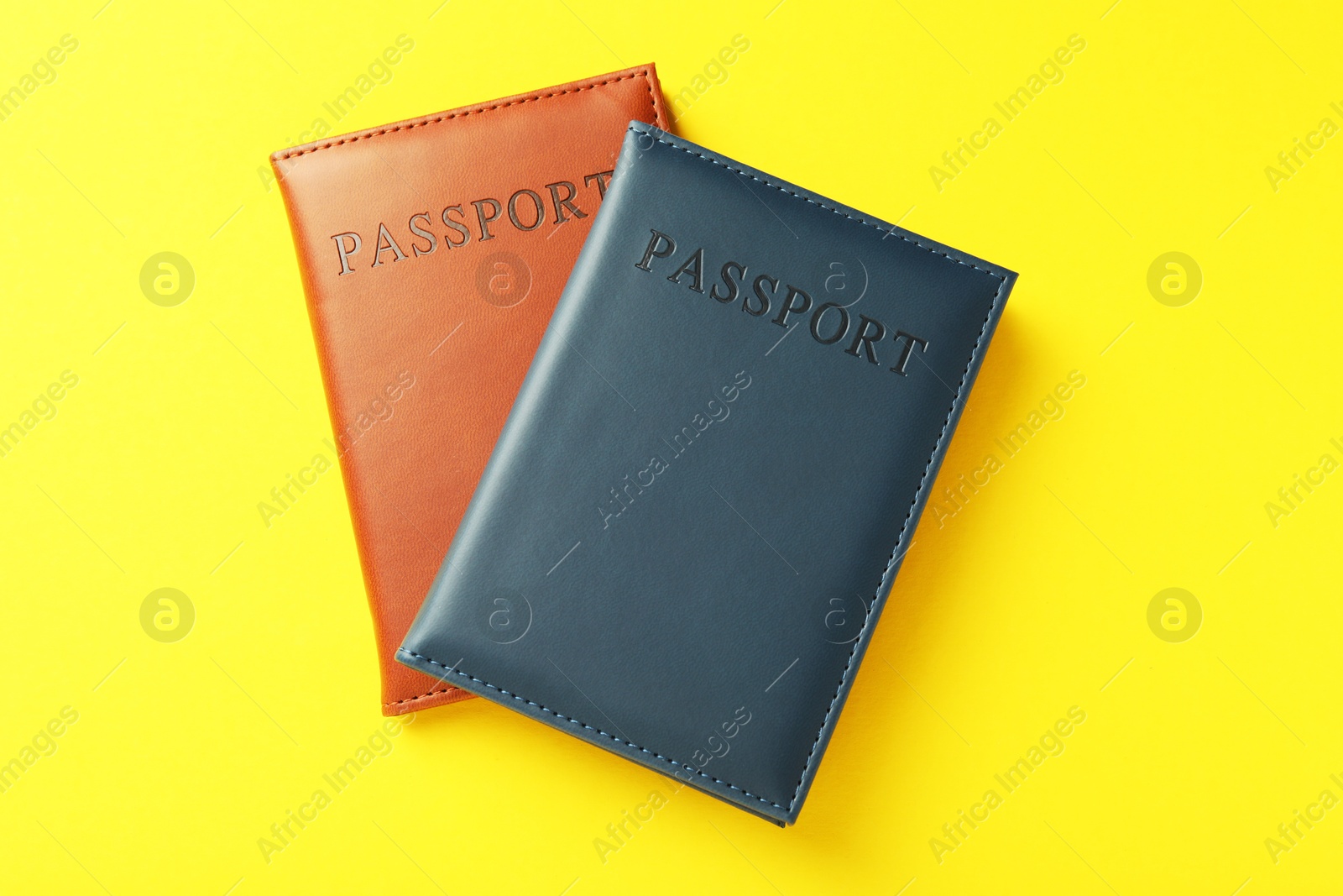 Photo of Passports in color covers on yellow background, top view