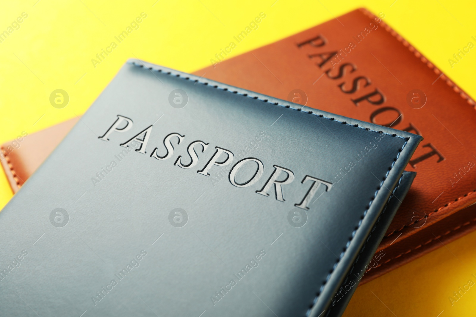 Photo of Passports in color covers on yellow background, closeup