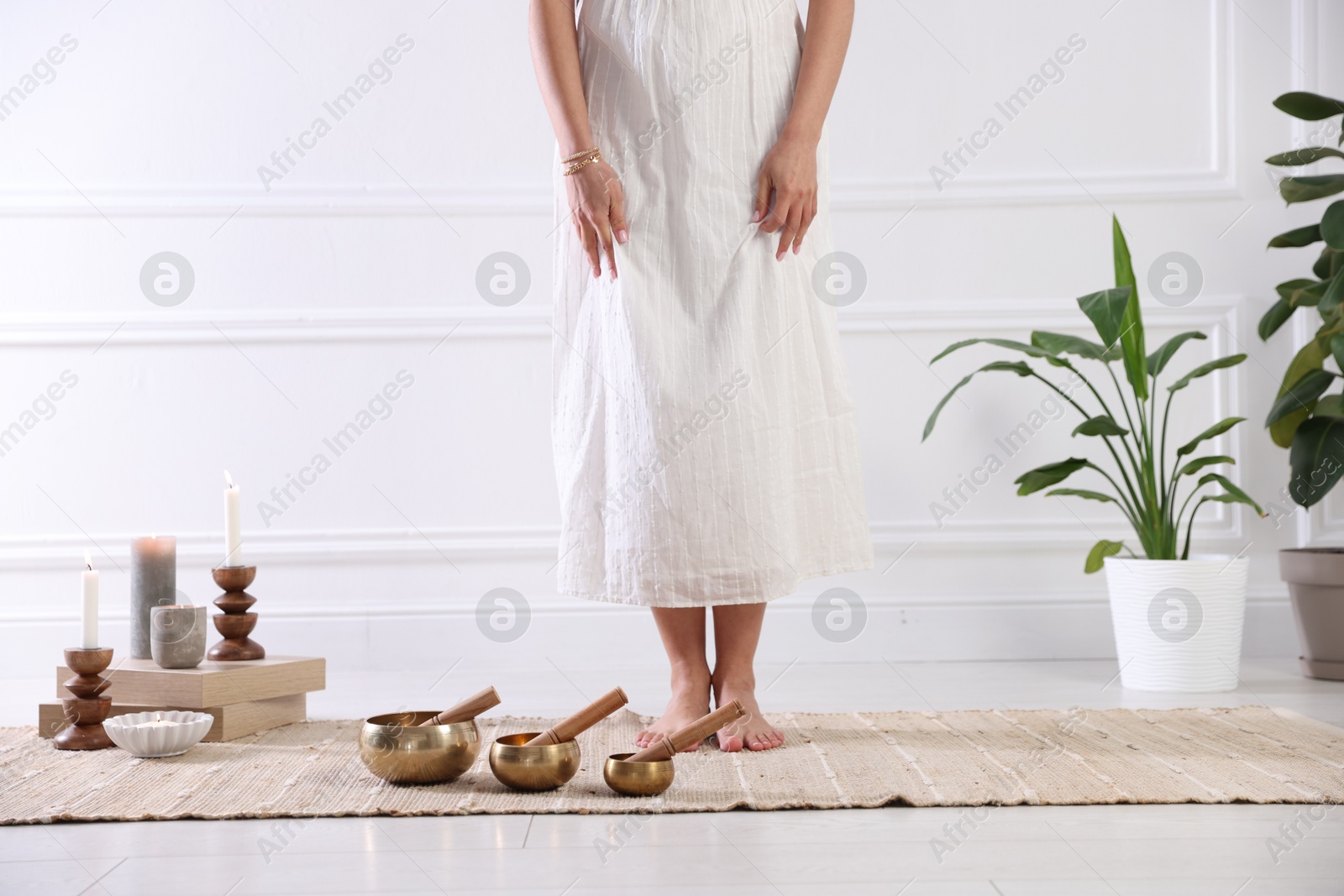 Photo of Woman with singing bowls on floor indoors, closeup