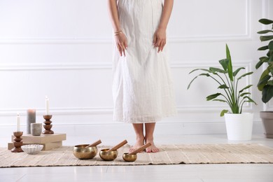 Photo of Woman with singing bowls on floor indoors, closeup