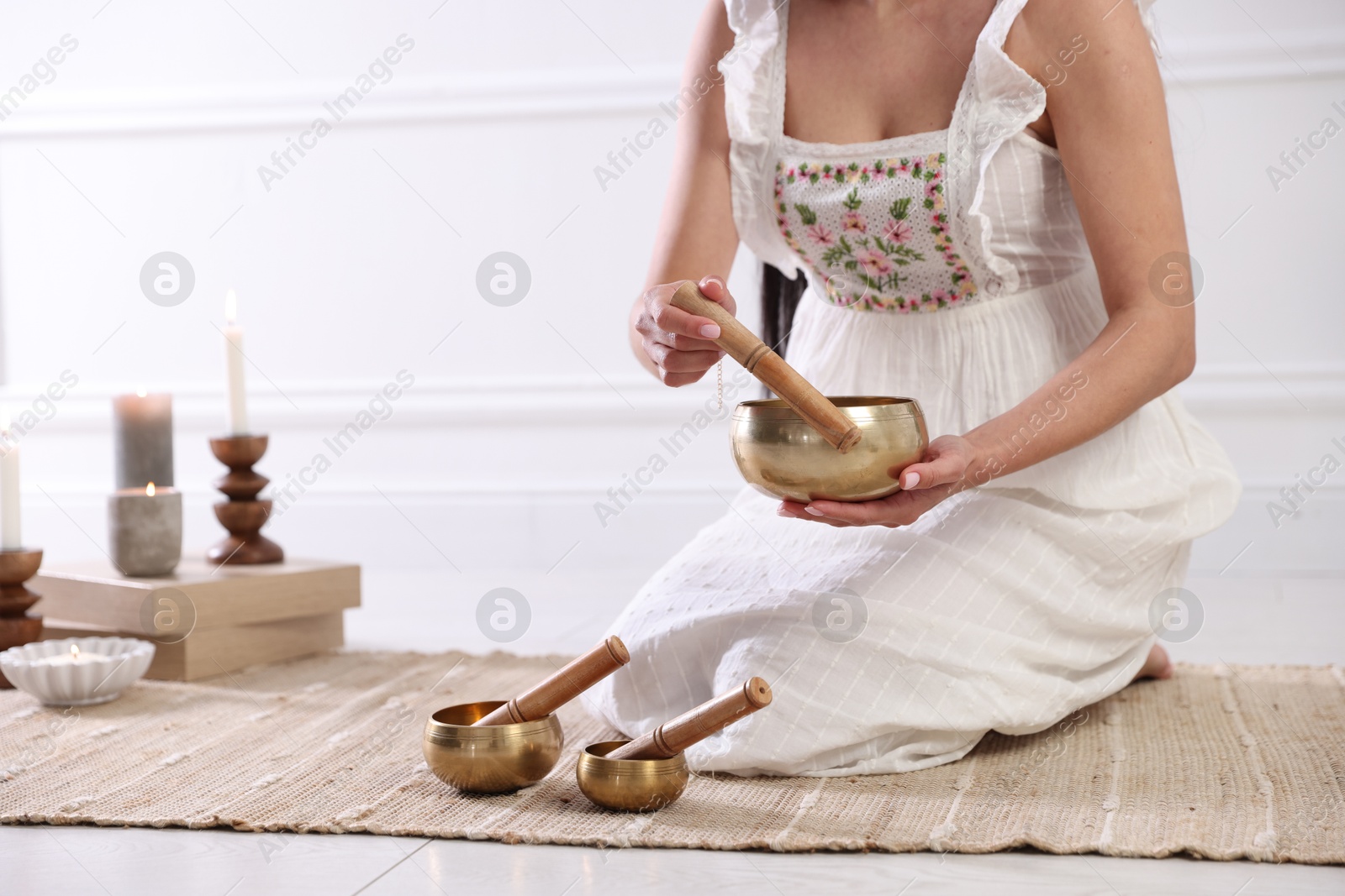 Photo of Woman with singing bowls on floor indoors, closeup