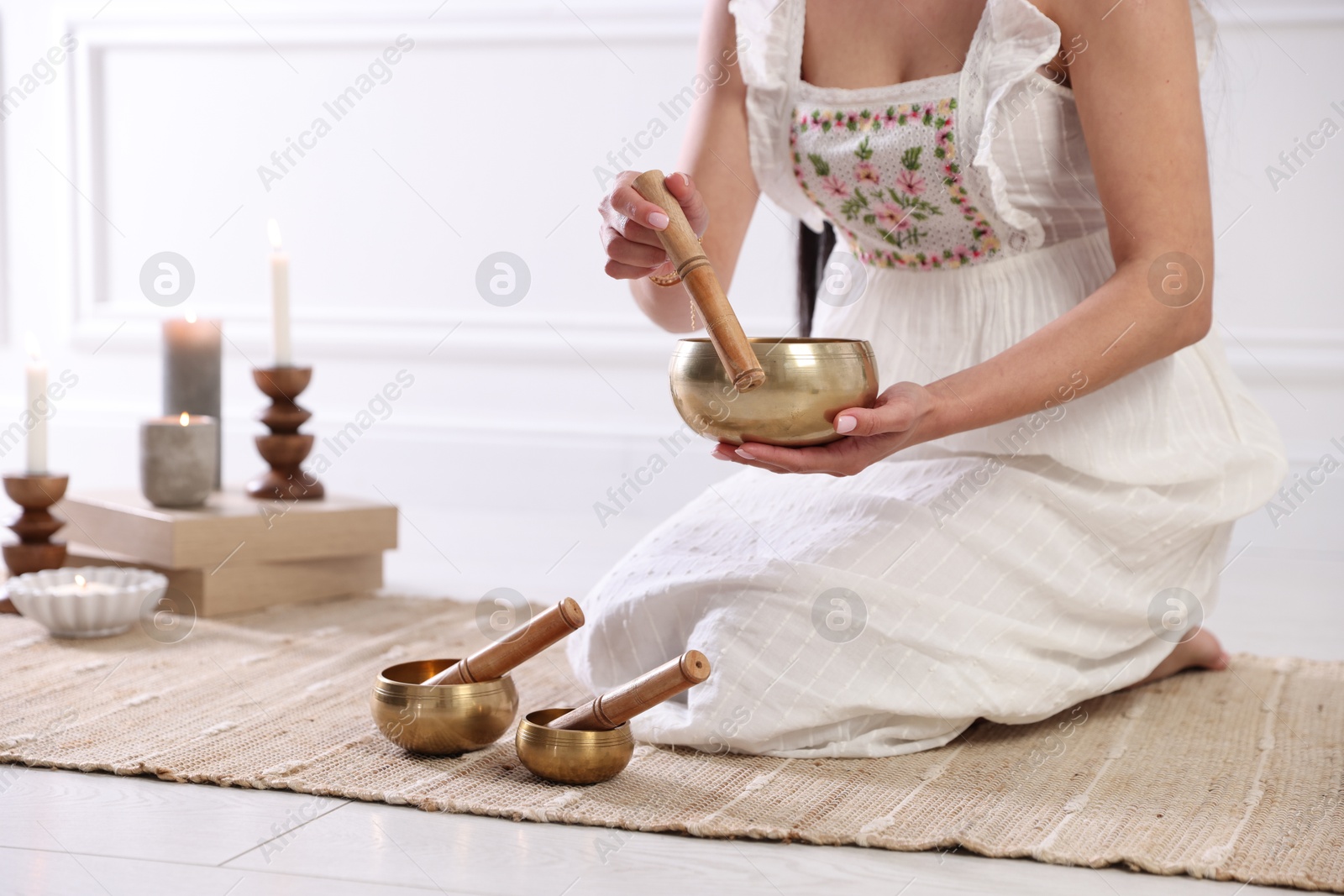 Photo of Woman with singing bowls on floor indoors, closeup