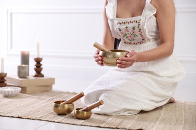 Photo of Woman with singing bowls on floor indoors, closeup