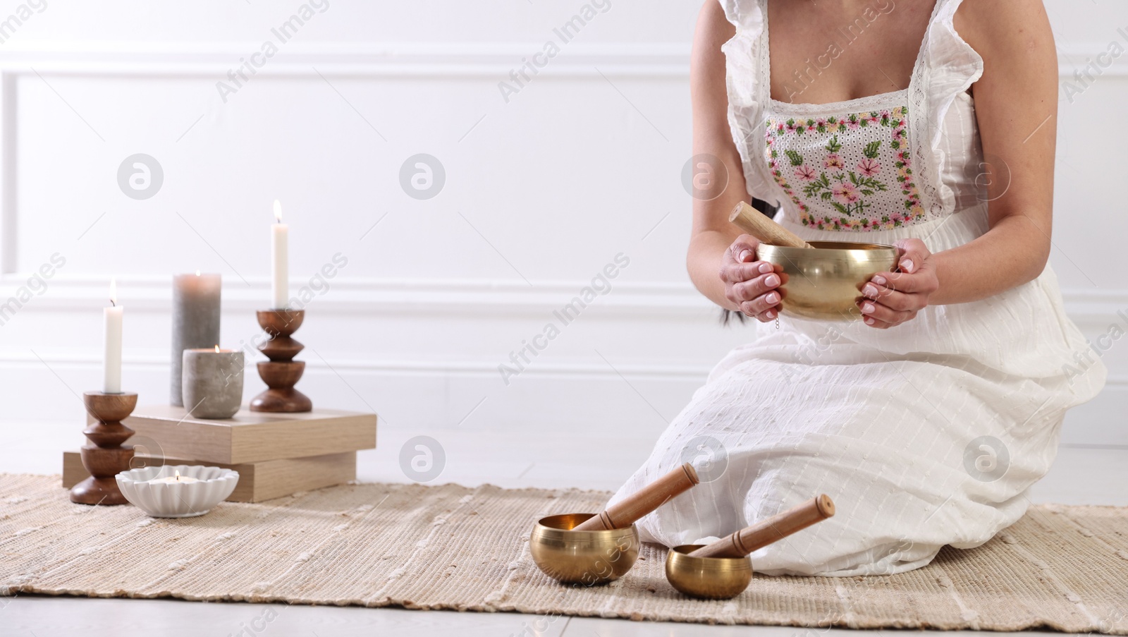 Photo of Woman with singing bowls on floor indoors, closeup. Space for text