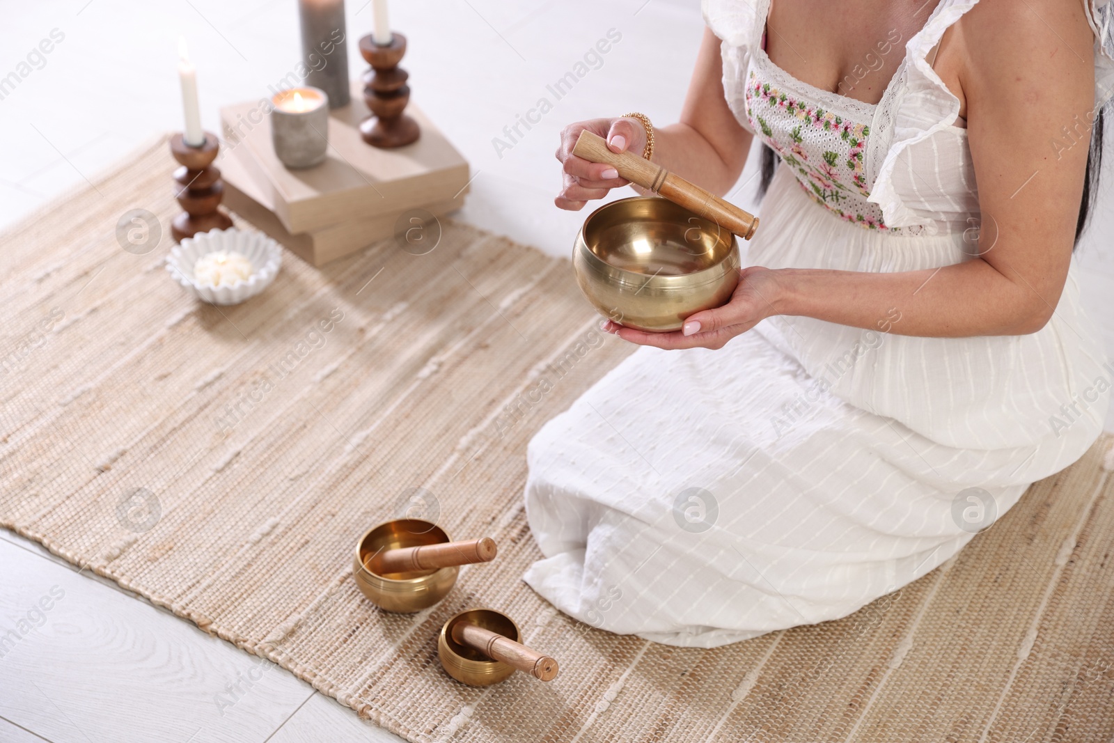 Photo of Woman with singing bowls on floor indoors, closeup