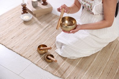 Photo of Woman with singing bowls on floor indoors, closeup