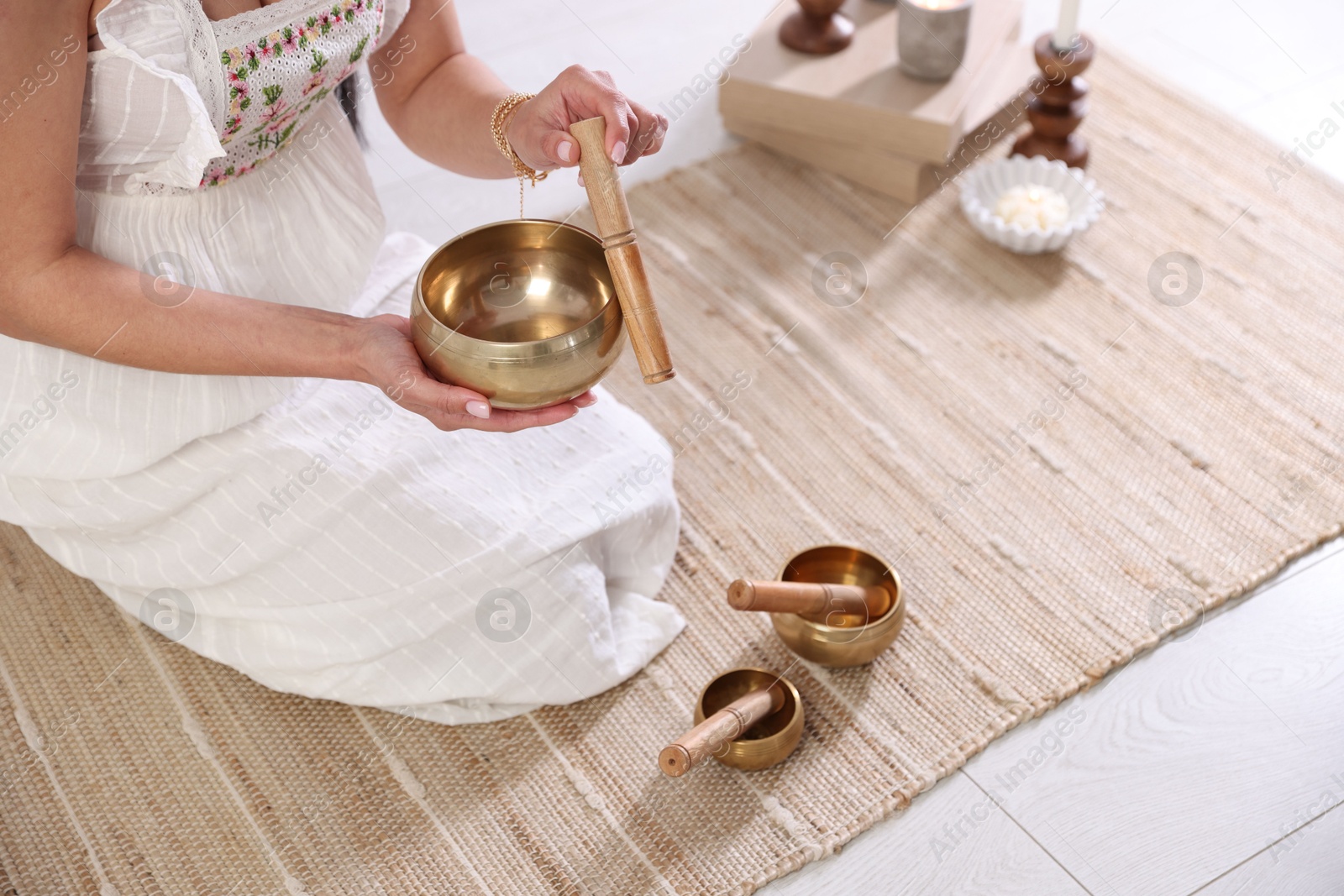 Photo of Woman with singing bowls on floor indoors, closeup