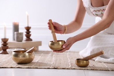 Photo of Woman with singing bowls on floor indoors, closeup