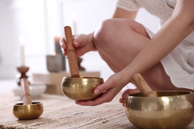 Photo of Woman with singing bowls on floor indoors, closeup