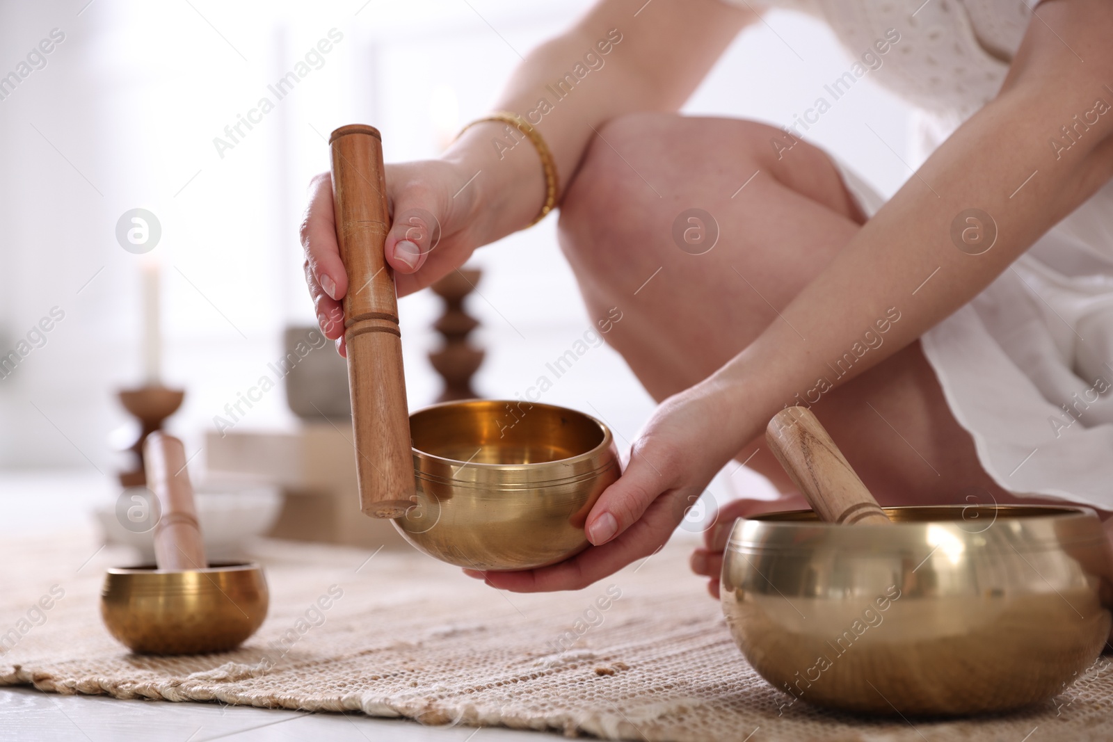 Photo of Woman with singing bowls on floor indoors, closeup