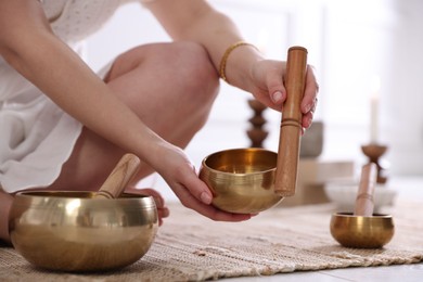 Photo of Woman with singing bowls on floor indoors, closeup