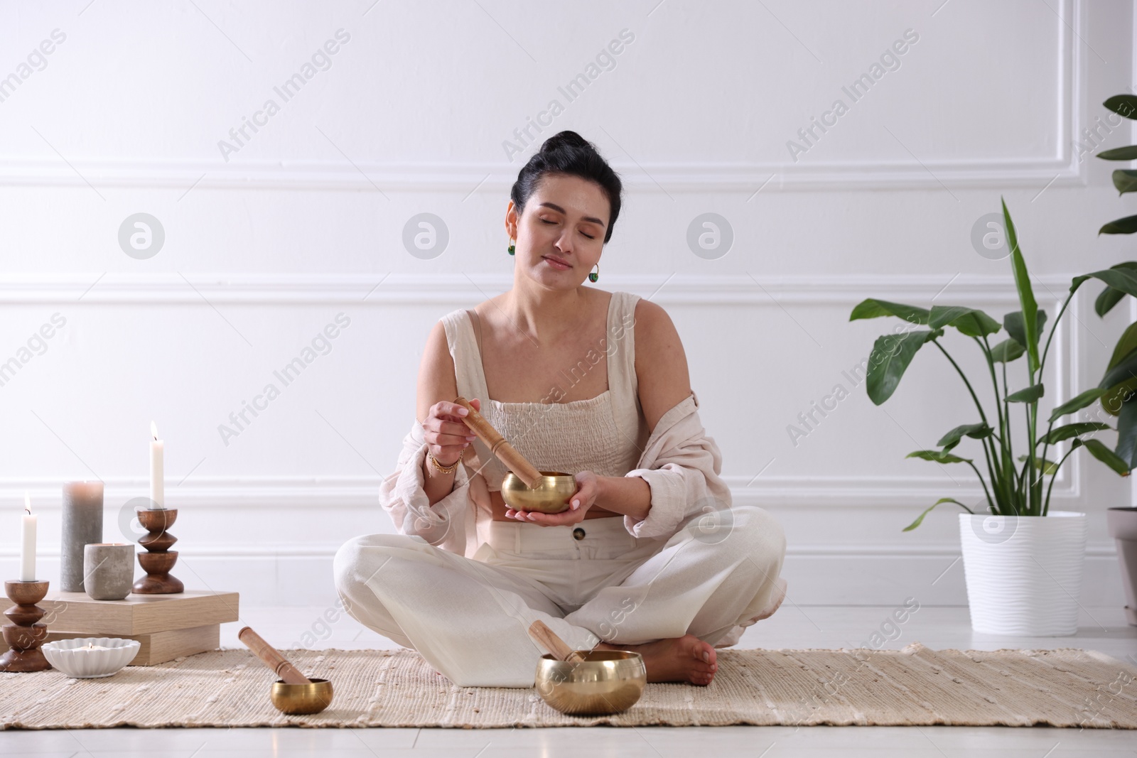 Photo of Woman with singing bowls on floor indoors