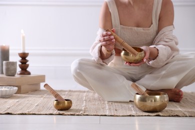 Photo of Woman with singing bowls on floor indoors, closeup