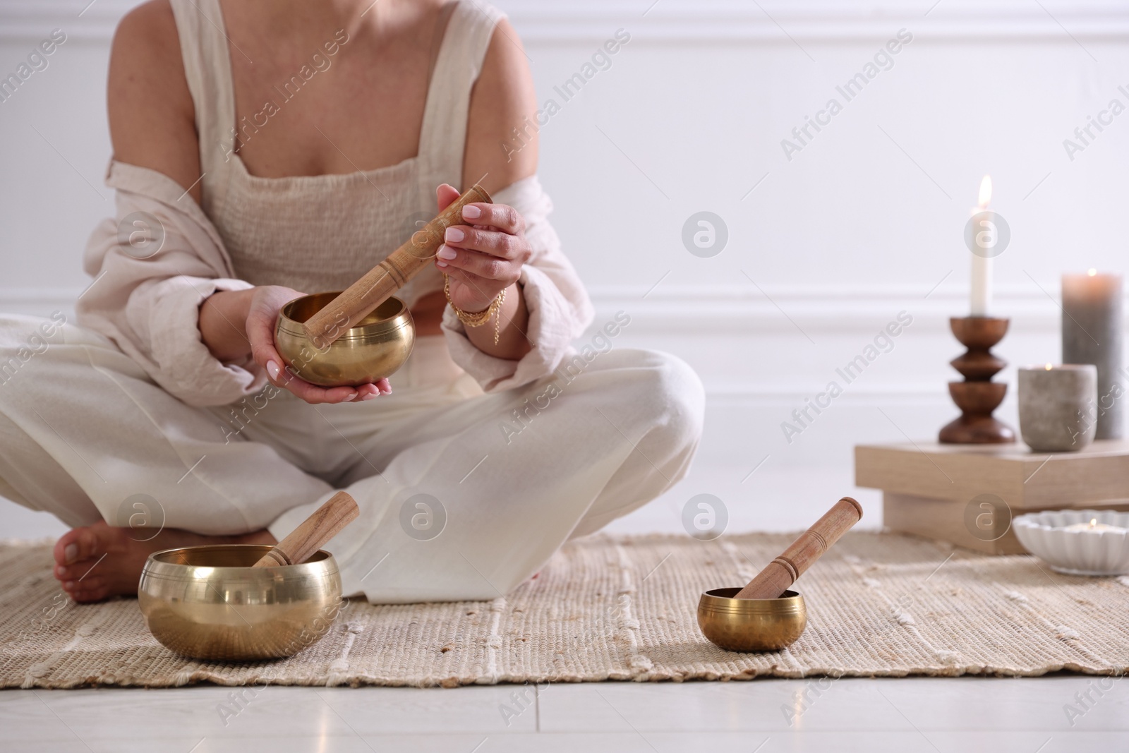 Photo of Woman with singing bowls on floor indoors, closeup