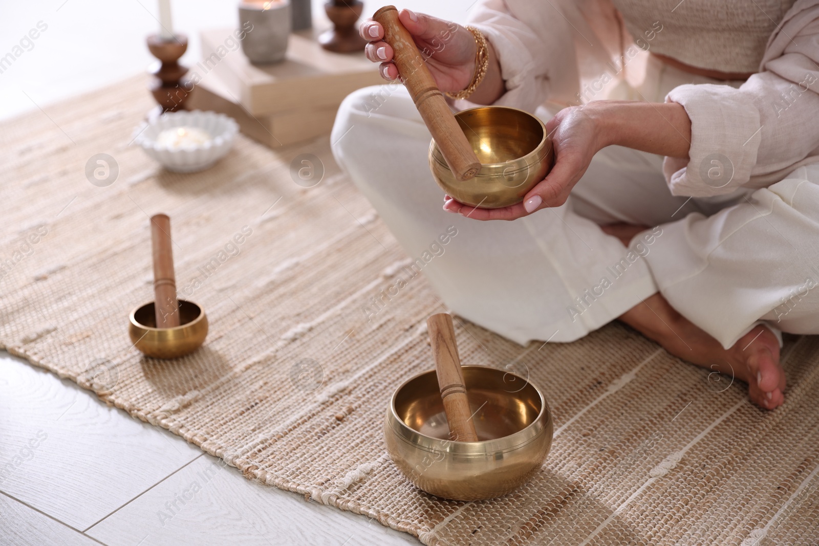 Photo of Woman with singing bowls on floor indoors, closeup