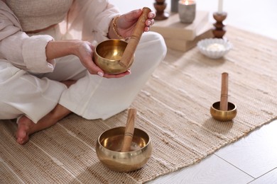 Photo of Woman with singing bowls on floor indoors, closeup