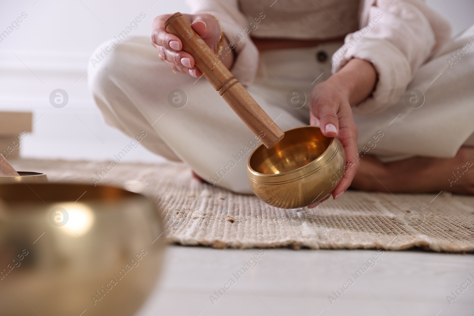 Photo of Woman with singing bowls on floor indoors, closeup