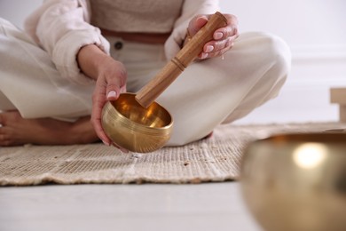 Photo of Woman with singing bowls on floor indoors, closeup