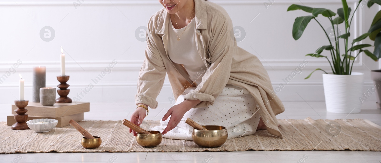 Photo of Woman with singing bowls on floor indoors, closeup