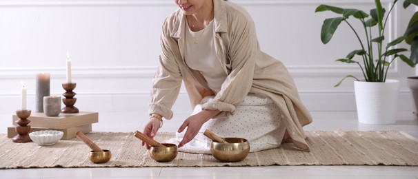 Woman with singing bowls on floor indoors, closeup