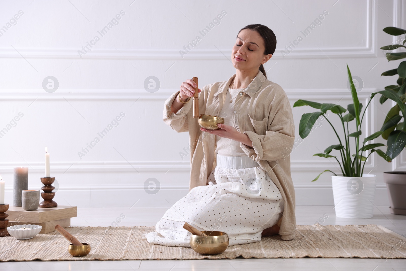 Photo of Woman with singing bowls on floor indoors. Space for text