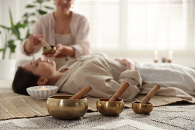 Photo of Woman undergoing singing bowl therapy indoors, selective focus. Space for text