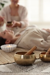 Woman undergoing singing bowl therapy indoors, selective focus