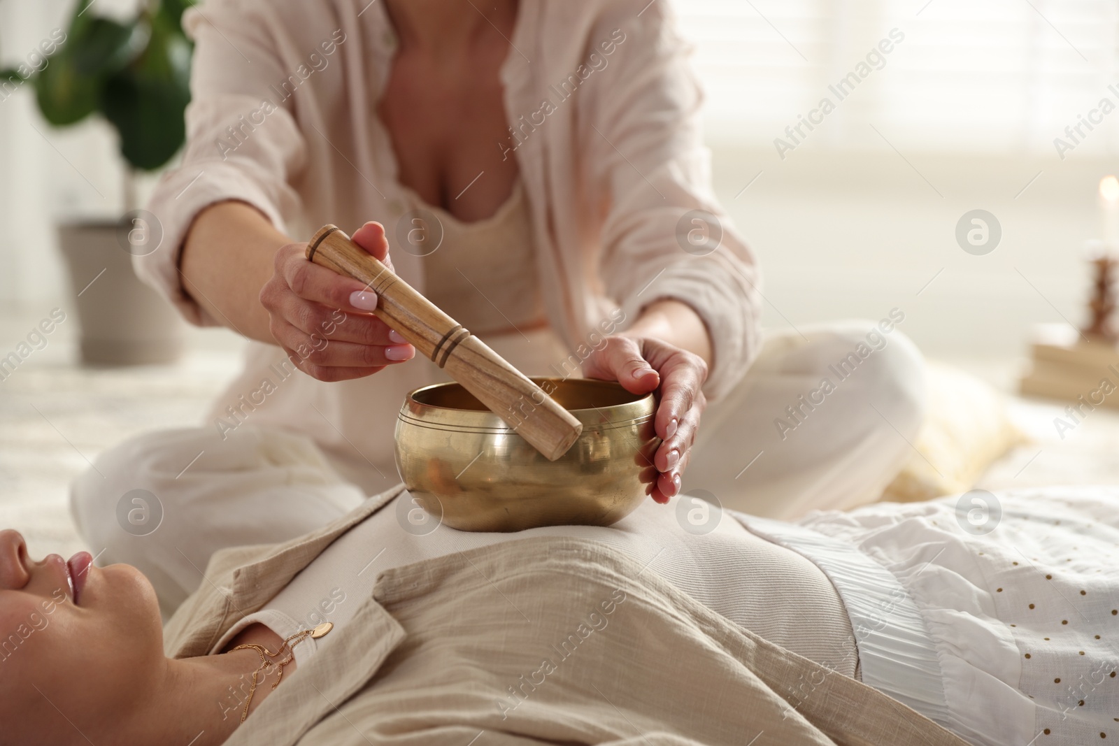 Photo of Woman undergoing singing bowl therapy indoors, closeup