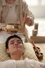 Photo of Woman undergoing singing bowl therapy lying on floor indoors