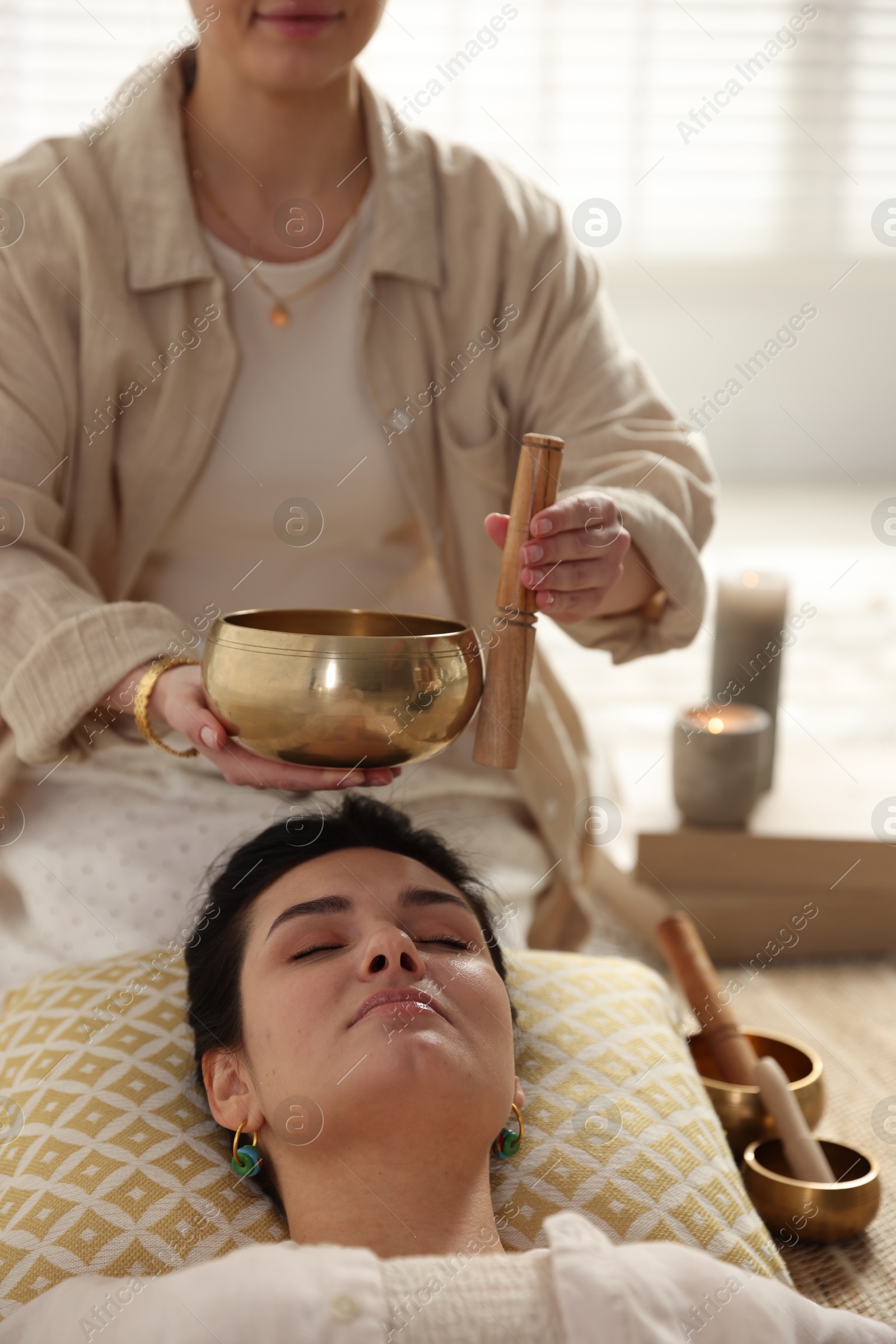 Photo of Woman undergoing singing bowl therapy lying on floor indoors