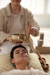 Woman undergoing singing bowl therapy lying on floor indoors