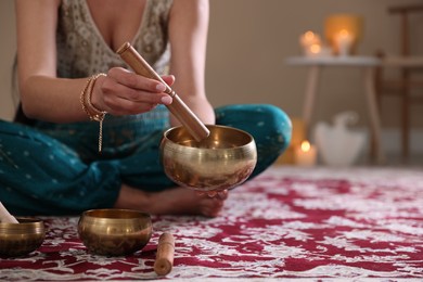 Photo of Woman with singing bowls and burning candles indoors, closeup