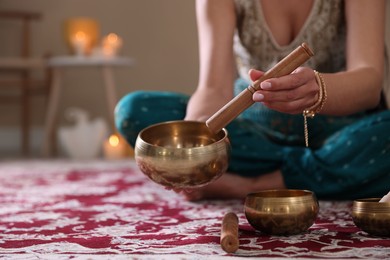 Photo of Woman with singing bowls and burning candles indoors, closeup