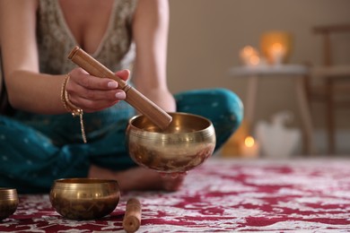 Photo of Woman with singing bowls and burning candles indoors, closeup