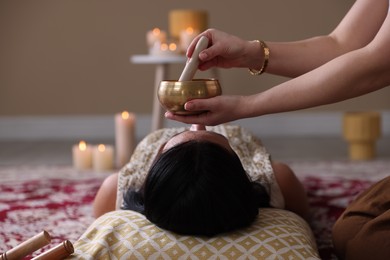 Photo of Woman undergoing singing bowl therapy lying on floor indoors