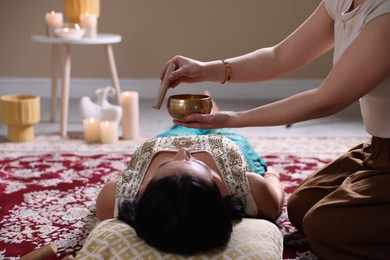 Photo of Woman undergoing singing bowl therapy lying on floor indoors