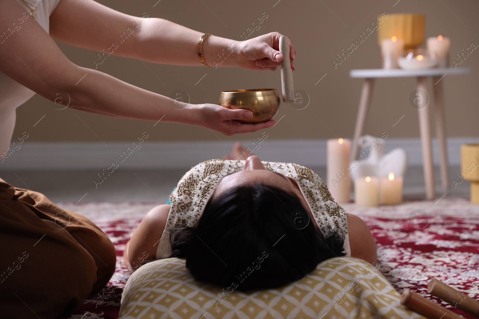 Photo of Woman undergoing singing bowl therapy lying on floor indoors